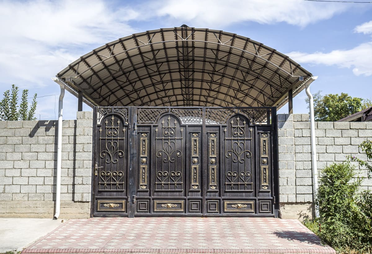 Metal sundurma altında dekoratif desenli ferforje bahçe kapısı